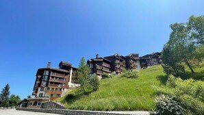 A multi-story hotel with balconies, set on a hillside with lush greenery. - 50m from ski slopes, 11st floor, balcony, ski locker, 45m², Valmorel (Valmorel)