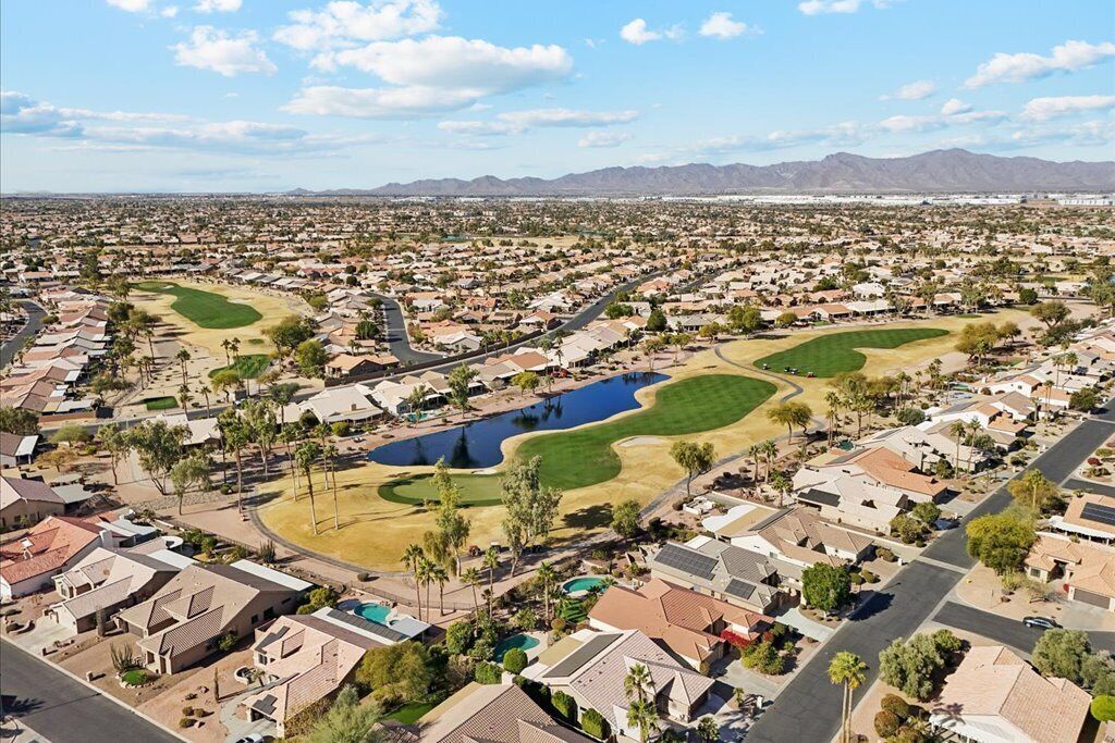 Un barrio residencial con casas, un campo de golf y una gran masa de agua.