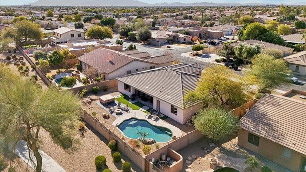 A residential area with houses, a swimming pool, and a mountainous backdrop. - Spacious 5-bedroom house with Heated Pool, hot tub and fire pit. (Goodyear)