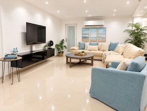 A modern living room with a flat-screen TV, a sofa, a coffee table, and a potted plant. - Breathtaking Beachfront Gem in Luquillo – Walk to Kiosks & Hidden Bars (Playa Fortuna)