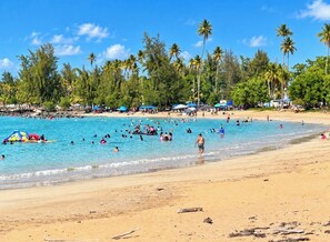 A beach with clear blue water, palm trees, and umbrellas. - Breathtaking Beachfront Gem in Luquillo – Walk to Kiosks & Hidden Bars (Playa Fortuna)
