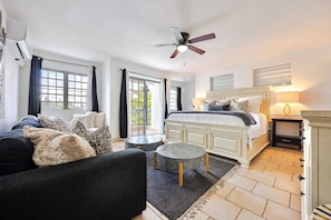 A bedroom with a bed, a ceiling fan, a window, and a small round table.