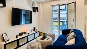Una sala de estar moderna con un televisor de pantalla plana grande, un sofá, otomanas y una consola decorada con adornos.