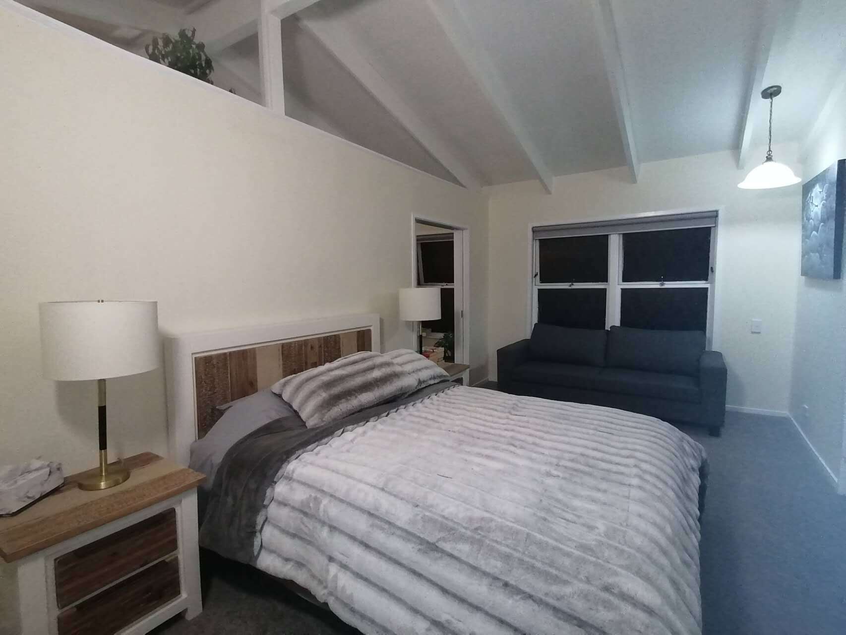A bedroom with a bed, bedside tables, a window, and a ceiling light.