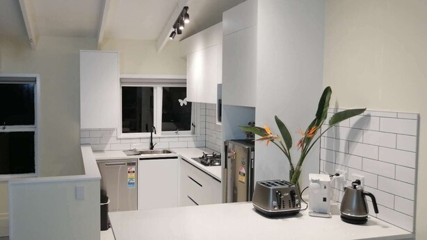 Una cocina moderna con armarios blancos, horno empotrado, pileta y una ventana decorada con una calcomanía de mariposa.