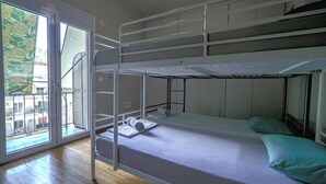 A bunk bed room with a window, a bed with a pillow, and a towel. - Cozy Corner (Athens)