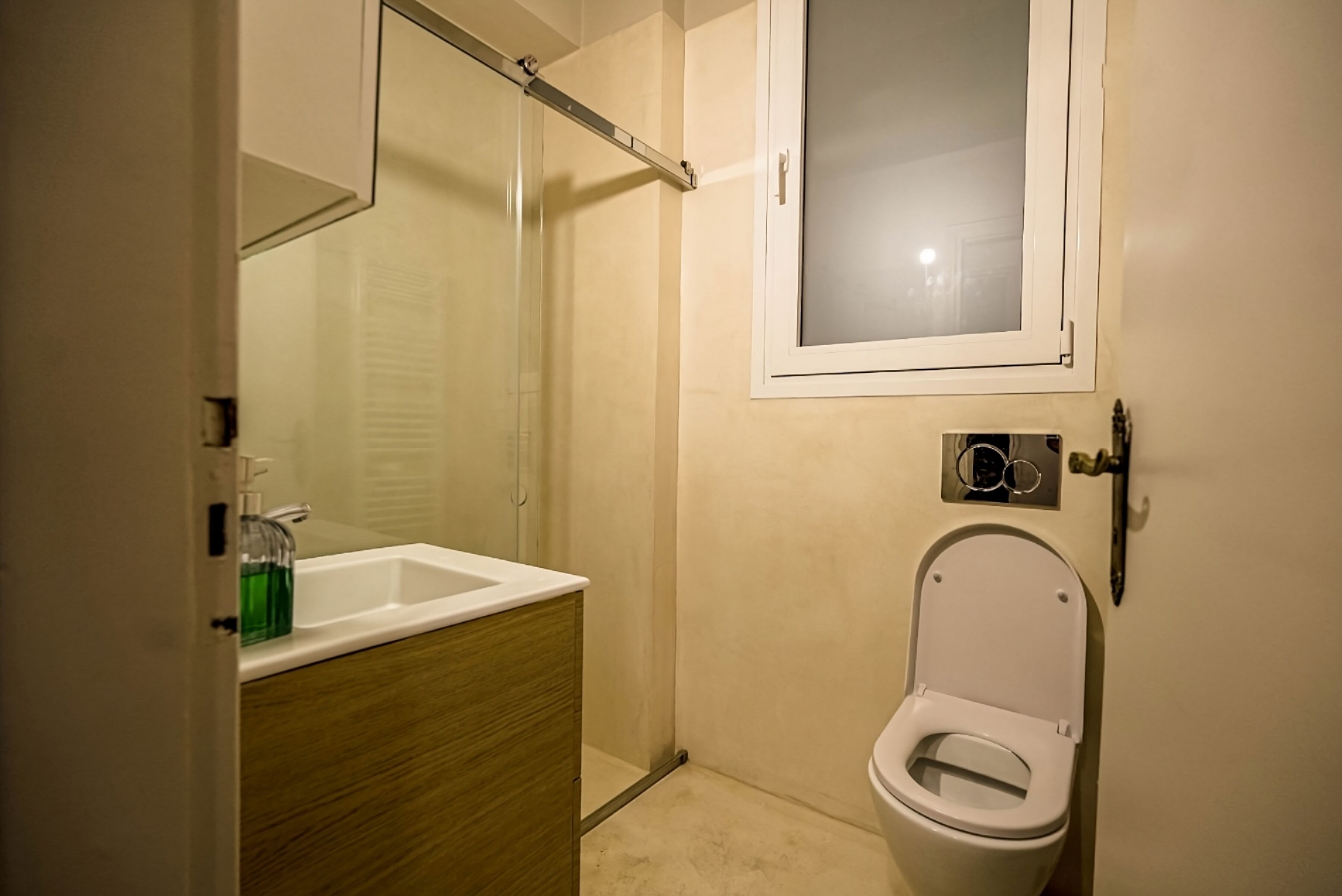 A small bathroom with a toilet, a sink, and a mirror.