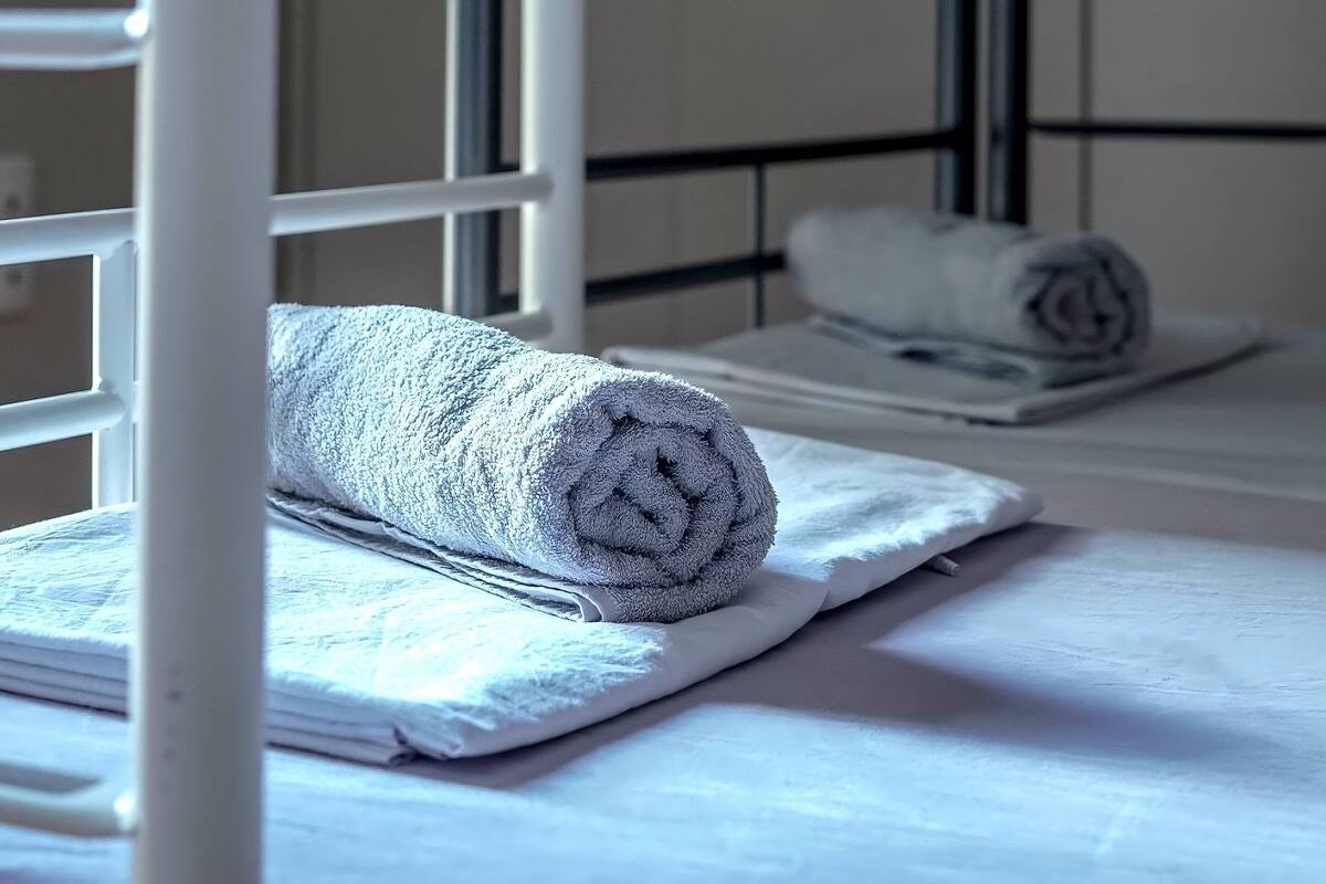 A bunk bed with a rolled towel on the lower bunk and a pillow on the upper bunk.
