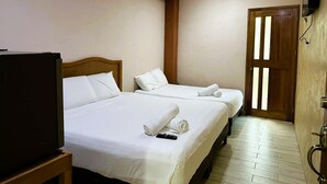 Une chambre d’hôtel avec deux lits, un ventilateur de plafond, une télévision et une porte en bois.