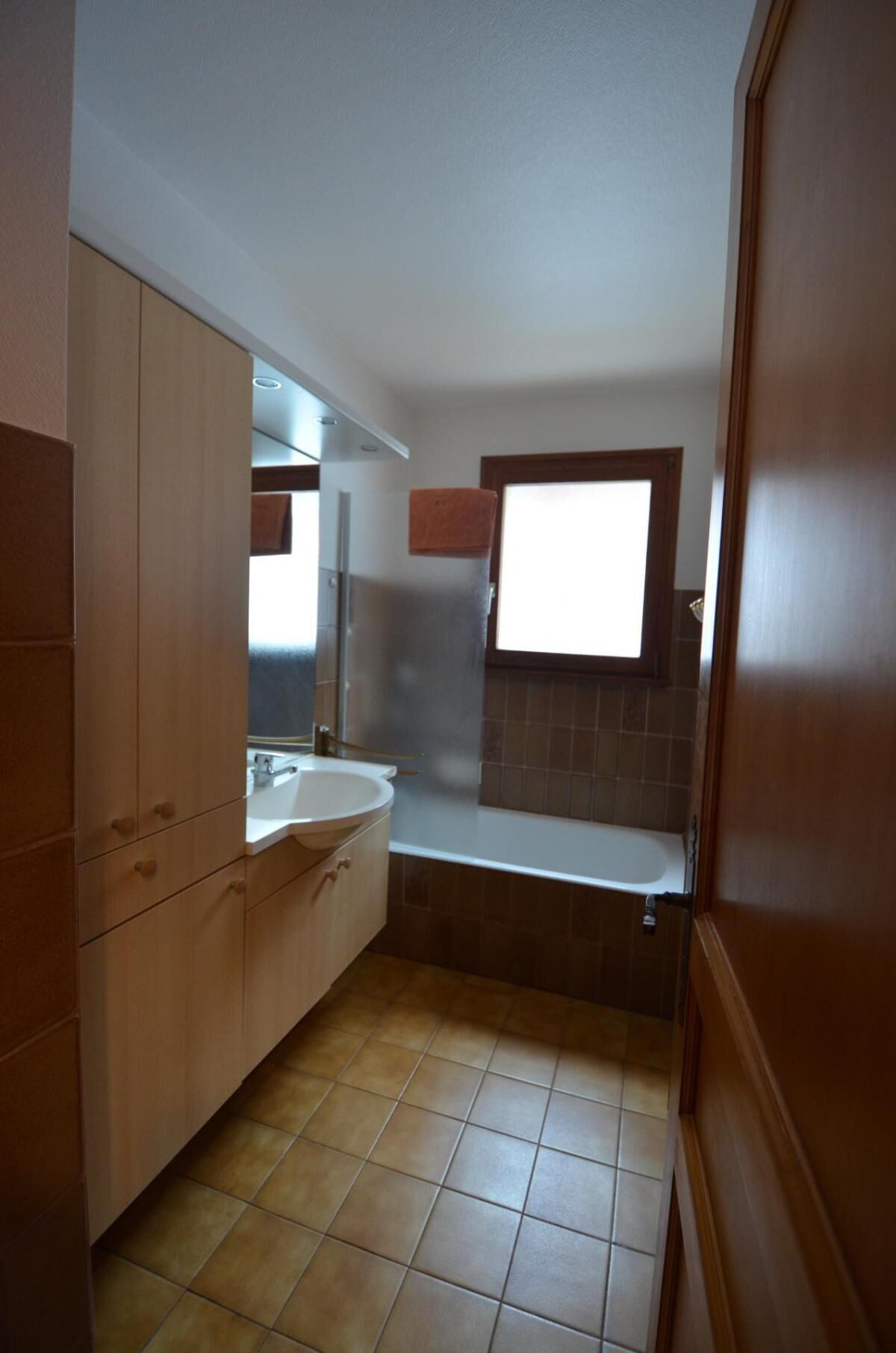 A small bathroom with a sink, mirror, and window.