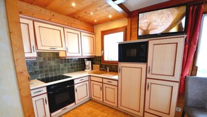 A compact kitchen with wooden cabinets, a microwave, and a coffee maker. - Wifi, 1st floor, balcony, parking, ski locker, 52m², Le Grand Bornand (Le Grand-Bornand)