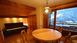 A cozy room with a wooden ceiling, a round wooden table, and a sofa.