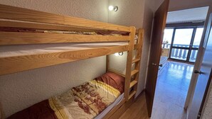 A bunk bed with a ladder, a small window, and a door leading to a balcony.