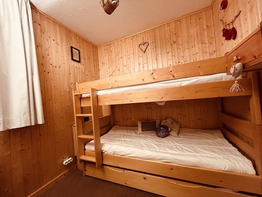 Een slaapkamer met een stapelbed, houten wanden, een ladder en een decoratie in de vorm van een hart.
