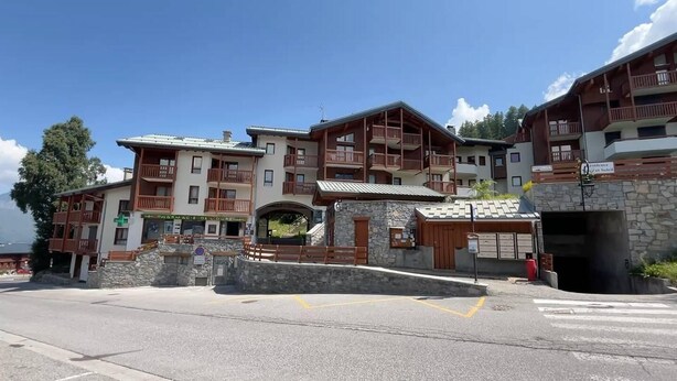 Un hotel de varios pisos con balcones, fachada de piedra y vistas a la montaña.