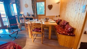 Una habitación acogedora con una mesa de comedor de madera, un banco con cojines estampados y una pared de madera.