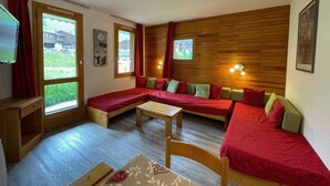 Une pièce chaleureuse avec un mur en bois, un ensemble de canapés, une petite table et un téléviseur.