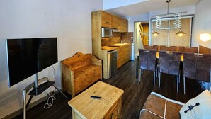 Un espacio habitable compacto con kitchenette, comedor y televisor.