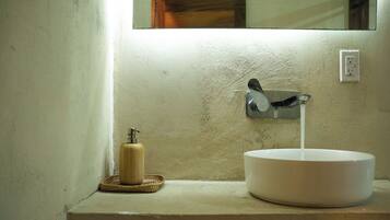 A bathroom with a white sink, a soap dispenser, and a mirror.