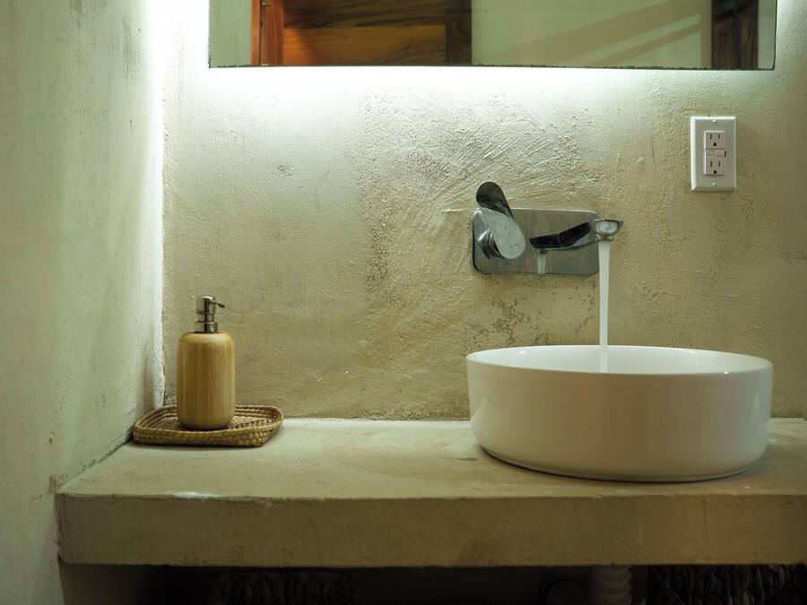 A bathroom with a white sink, a soap dispenser, and a mirror.