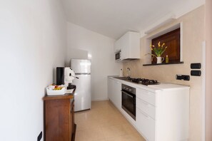 A compact kitchen with white cabinets, a refrigerator, a stove, and a microwave.