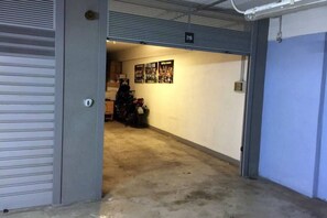 Eine Garage mit einem Motorrad, einer Tür mit der Aufschrift '219' und einer Wand voller Plakate.