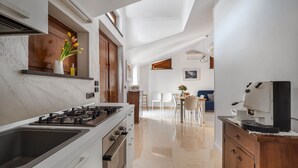Une cuisine moderne équipée d’une cuisinière à gaz, d’un évier et d’un coin repas avec une table et des chaises.
