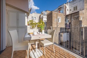 A balcony with a table and chairs, a potted plant, and a view of neighboring buildings. - Il Tulipano | Apartment with Private Terrace in the Centre of Vico Equense (Vico Equense)