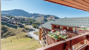 Un bâtiment en bois doté d’un balcon donnant sur un paysage montagneux et une petite ville.