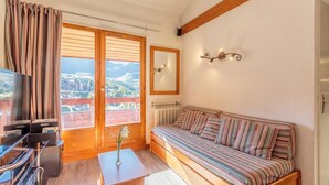 Un salon chaleureux avec un canapé à rayures, un téléviseur et une vue sur les montagnes grâce à de grandes fenêtres.