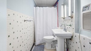 A small bathroom with a toilet, sink, and shower curtain. - Workforce Suites (Peru)