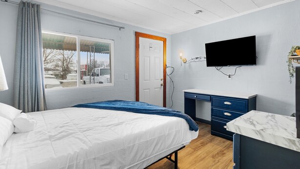 A bedroom with a bed, a desk, a TV, and a window with curtains. - Workforce Suites (Peru)