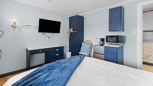 A bedroom with a bed, a desk, a chair, a television, and a microwave. - Workforce Suites (Peru)