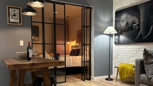 Een moderne woonkamer met een houten eettafel, een bank en een groot kunstwerk van een olifant aan de muur.