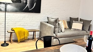 Een moderne woonkamer met een grijze bank, een houten salontafel en een zwart hanglamp.