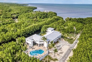 An aerial view of a modern house with a swimming pool, surrounded by dense greenery and a view of the sea. - Large Oceanfront Private Oasis perfect for a Wedding, Family or Corporate Event (Key Largo)