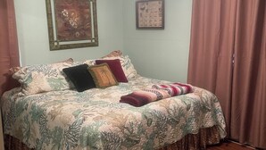 A bedroom with a bed, a ceiling fan, a framed picture, and a window with curtains. - Charming 2-bedroom house with WiFi, AC in welcoming Port Lavaca (Port Lavaca)