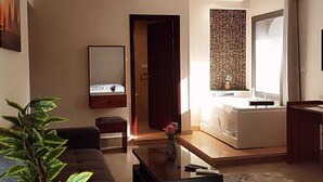 A modern living room with a sofa, coffee table, and a large mirror. There is a door leading to another room and a window with curtains. - Zahira pyramids view (Giza)