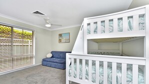 Quarto com beliche, sofá e ventoinha no teto.