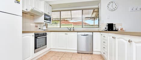 A kitchen with white cabinets, a microwave, oven, and dishwasher.