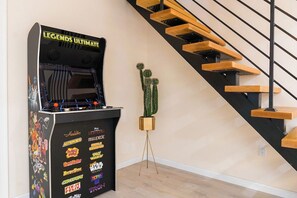 Une salle d’arcade proposant une sélection de jeux vidéo, une sculpture de cactus et un escalier en bois.