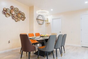Un coin repas avec une table ronde, six chaises et un lustre.