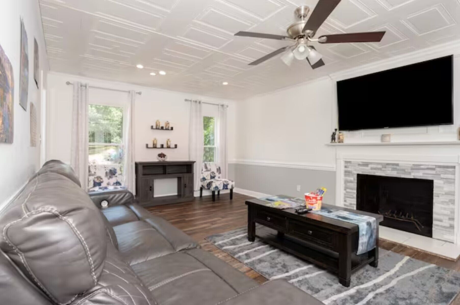 A living room with a leather sofa, a coffee table, a fireplace, and a TV mounted on the wall.