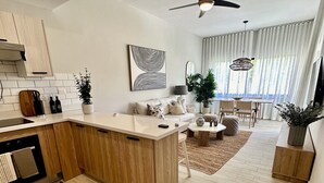 Een moderne keuken met houten kastjes, een centraal eiland en een zithoek met een tafel en stoelen.
