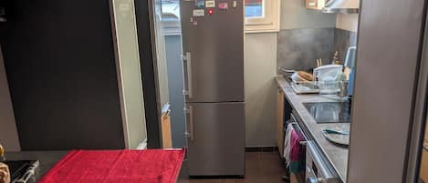 A compact kitchen with a refrigerator, microwave, and washing machine.