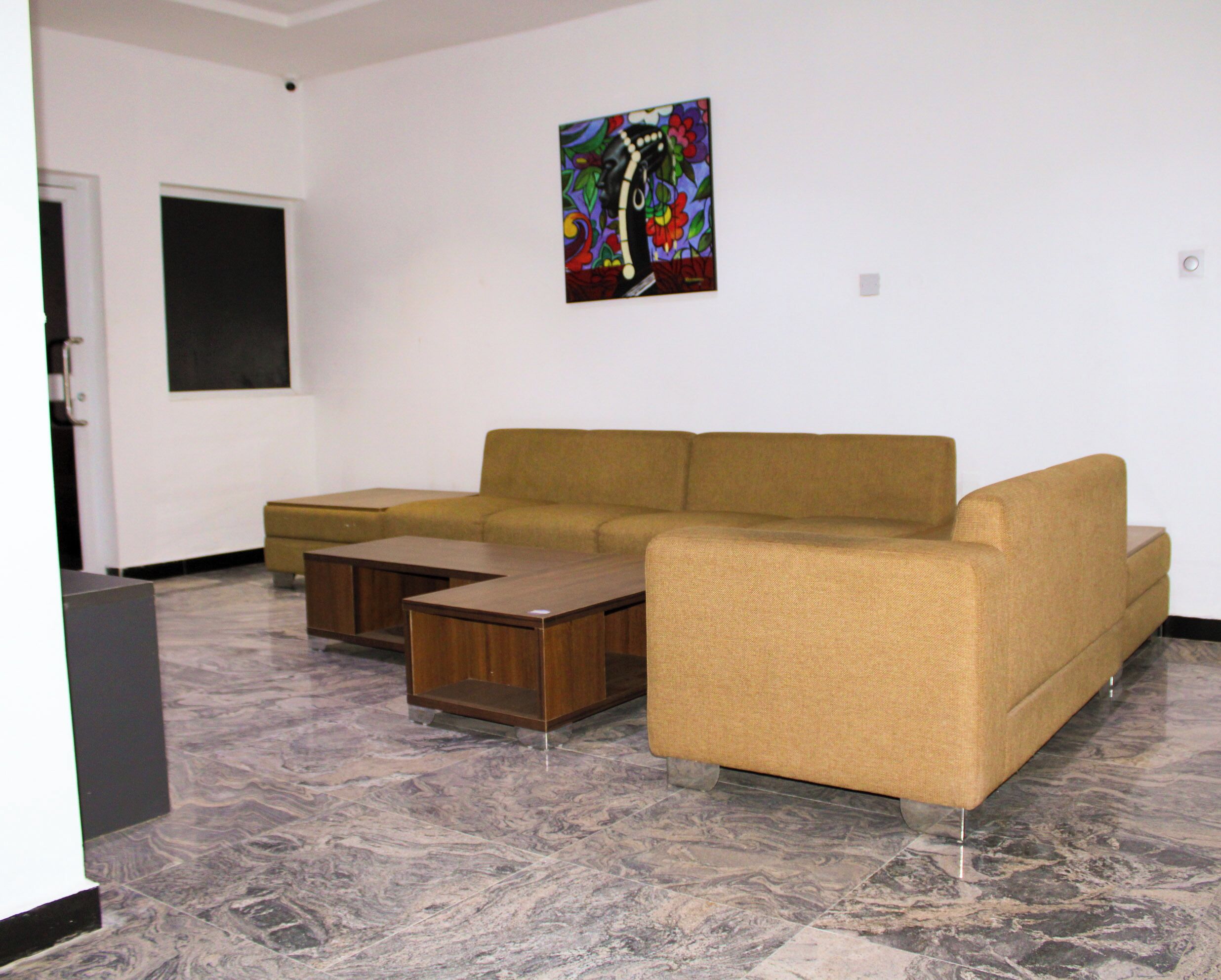 A living room with a sofa, a coffee table, and a painting on the wall.