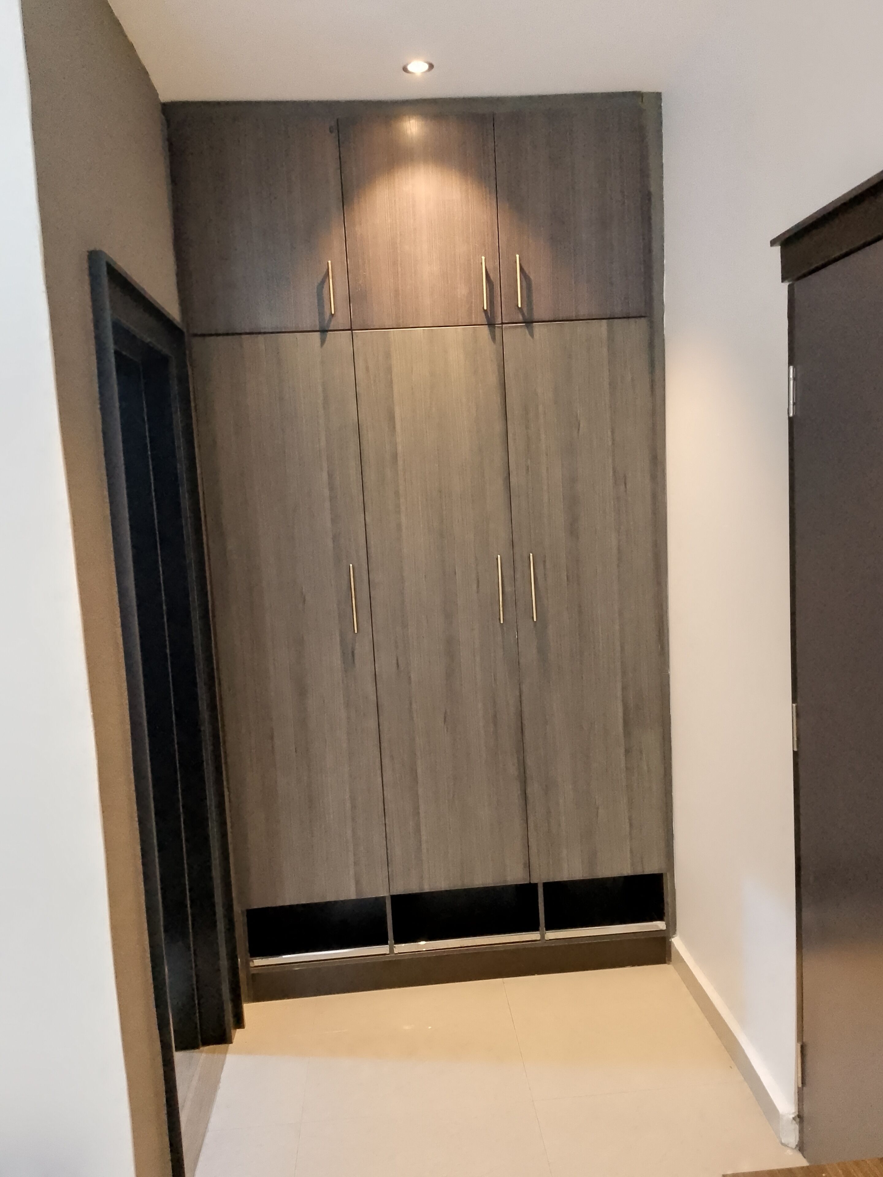 A hallway with a large wardrobe featuring two doors and a central panel.