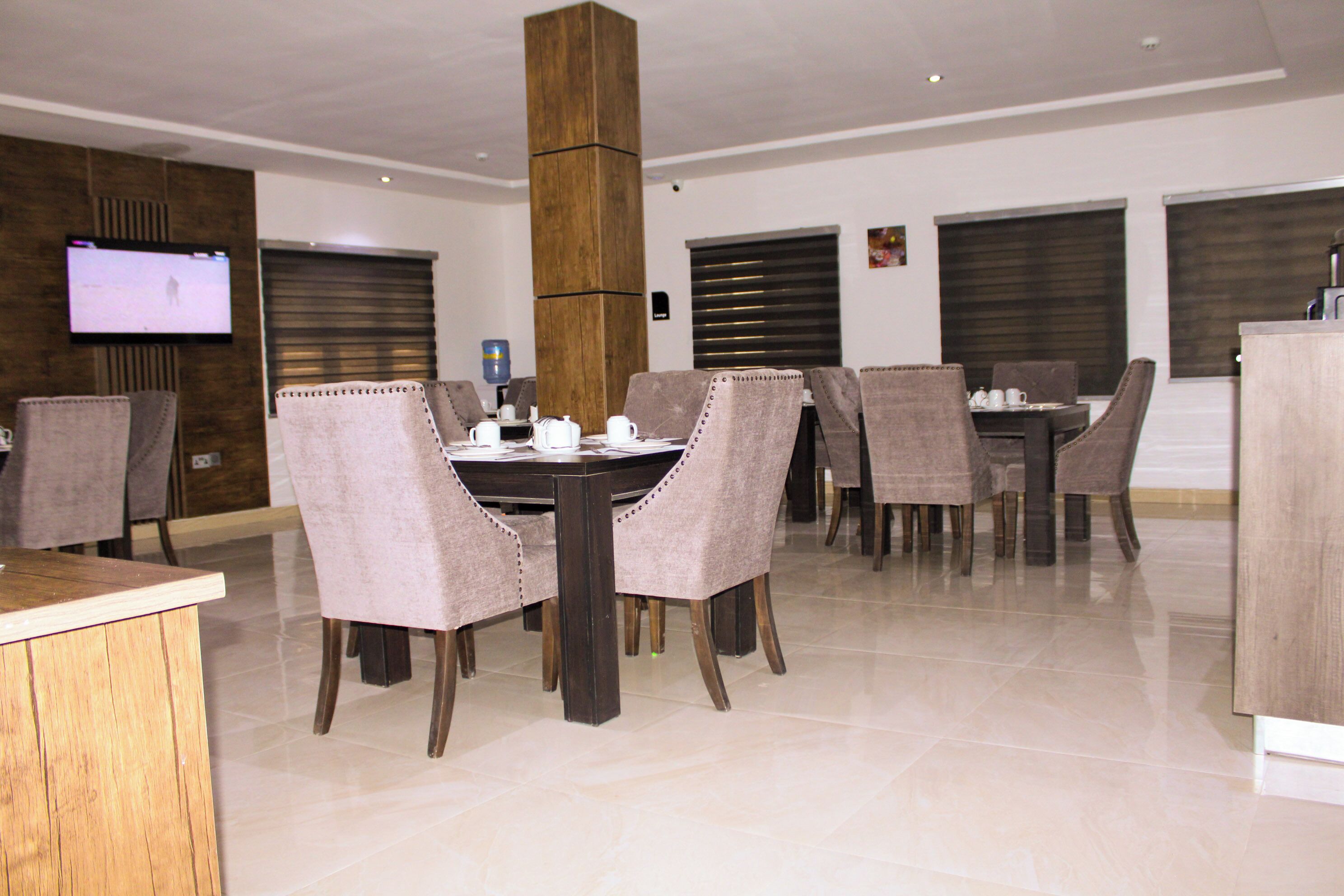 A dining area with a wooden central column, beige chairs, and a round table with a coffee set.