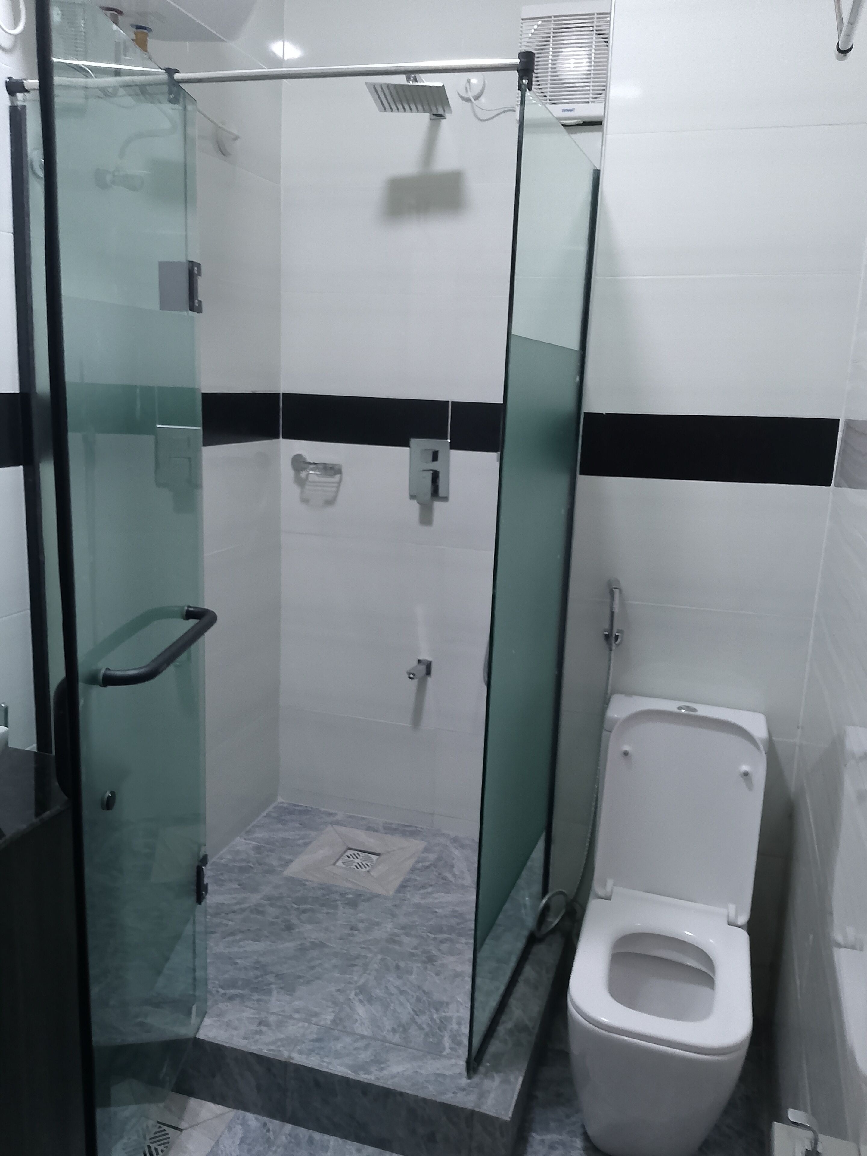 A bathroom with a glass-enclosed shower, a toilet, and a sink.