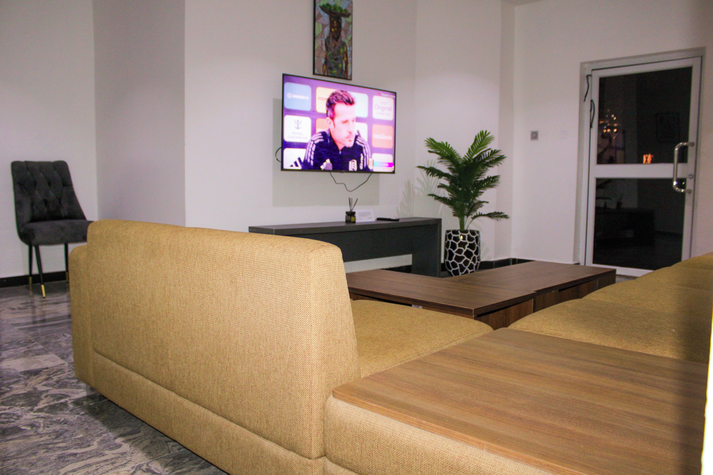 Een woonkamer met een bank, een salontafel en een flatscreen televisie die aan de muur is bevestigd.